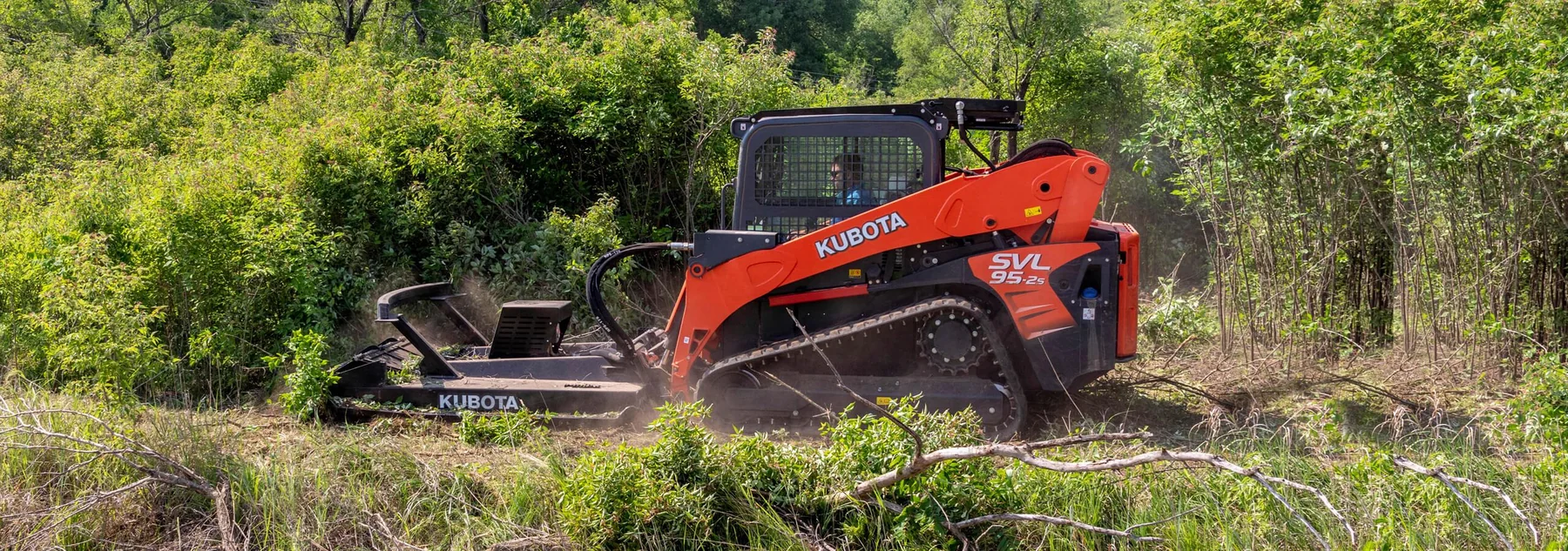 Compact track loader brush hogging a grassy field