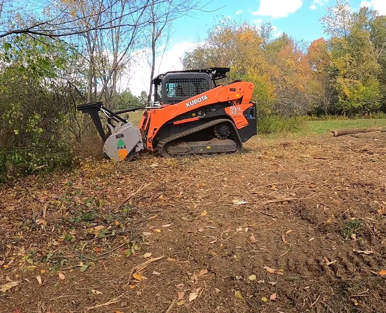 Compact track loader doing forestry mulching at a wooded property